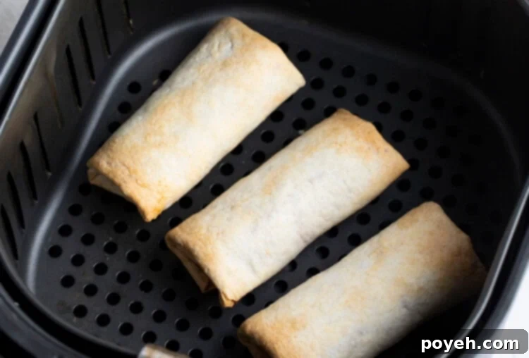 Perfectly cooked burritos glowing golden brown, showing their crispy texture within an air fryer basket.