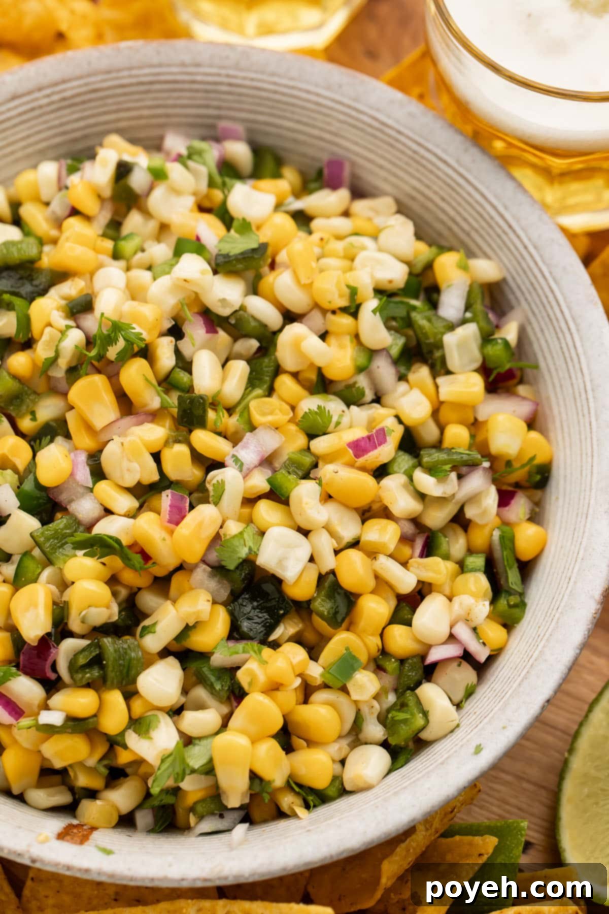 Close-up overhead view of a fresh bowl of roasted chili corn salsa, showcasing the vibrant colors of corn, red onion, cilantro, and roasted pepper.