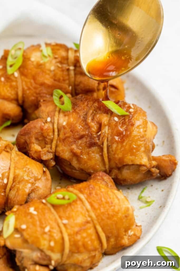 Rich sauce being spooned generously over perfectly cooked chicken chashu slices on a pristine white plate, garnished with fresh green scallions.