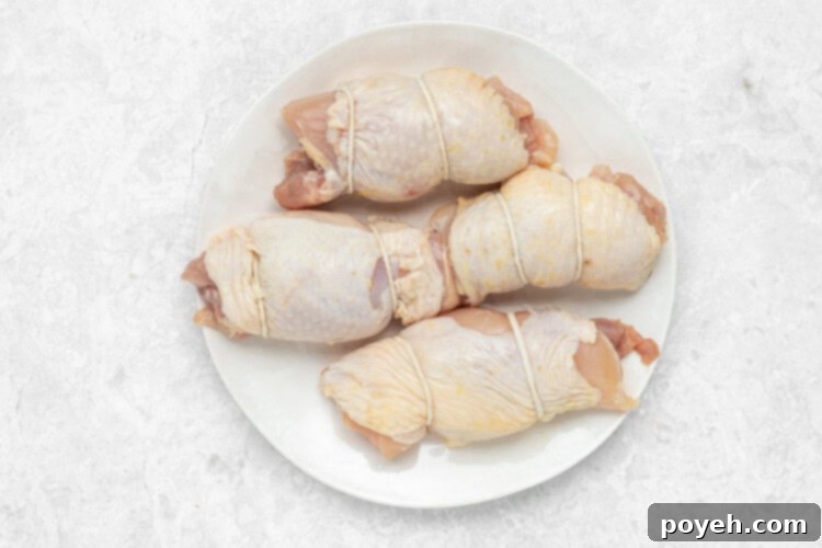 Step 1: Rolling and tying chicken thighs with cooking twine.