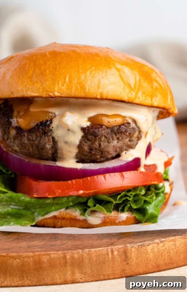 Close up photo of buffalo burger with burger sauce, tomato, onion, and lettuce on a bun