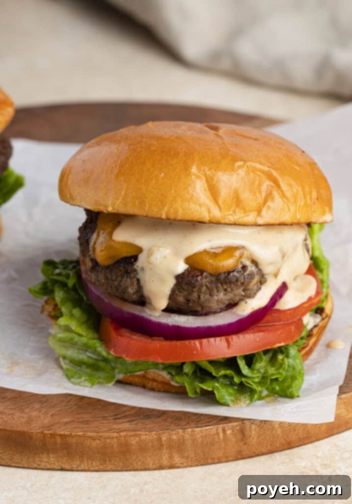 Buffalo burger with burger sauce, onion, tomato, lettuce on a bun, sitting on a wooden cutting board
