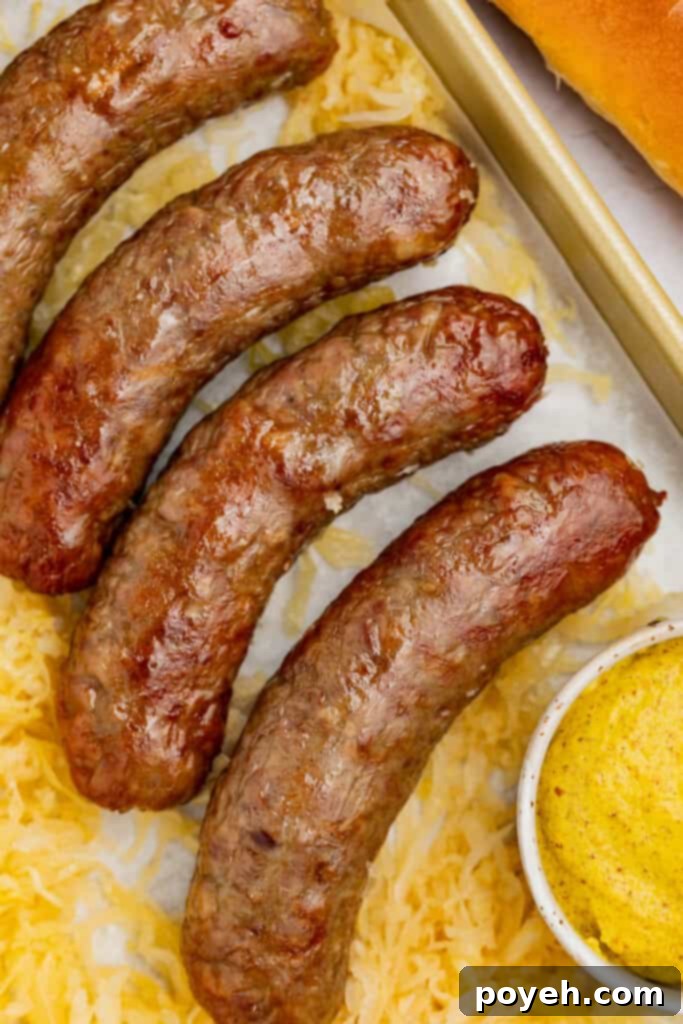 A close-up view of perfectly browned and juicy air fryer brats, with a dollop of classic yellow mustard on the side, highlighting their delicious crispiness.