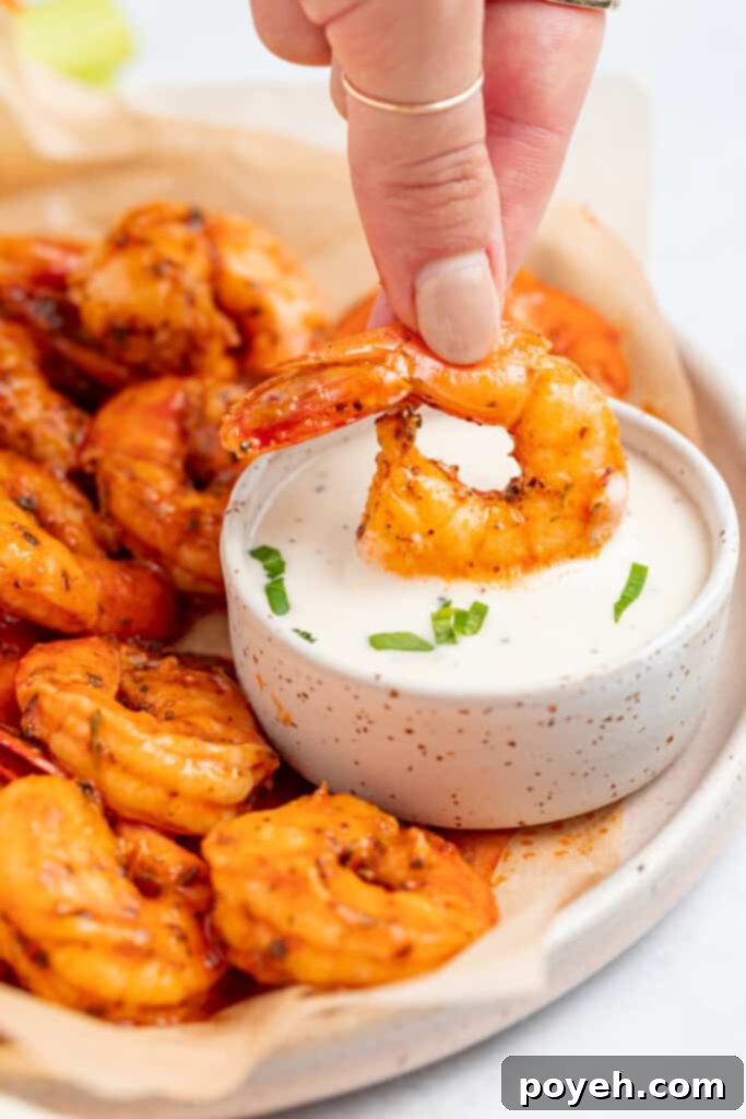 Crispy buffalo shrimp being dipped into a bowl of creamy ranch dressing, highlighting its vibrant color and tempting texture.