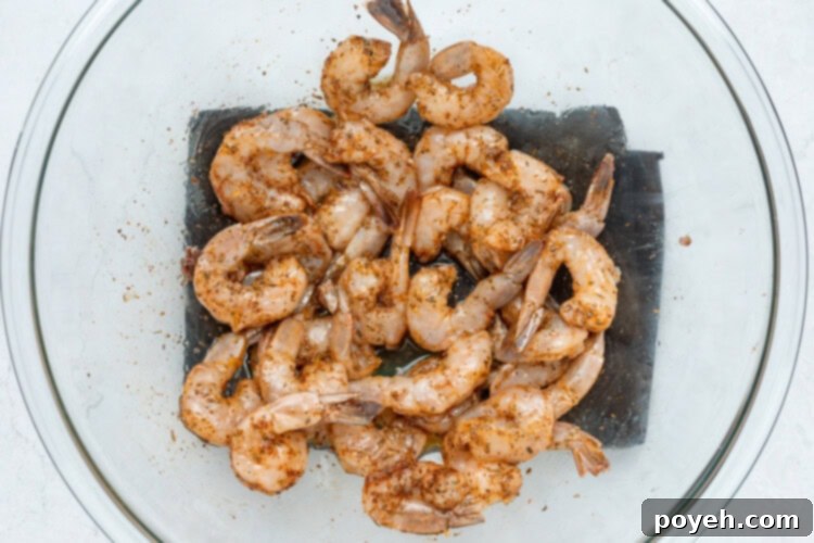Shrimp being tossed with Cajun seasoning and olive oil in a bowl.