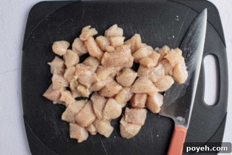 Chopped chicken breasts on a black cutting board with a sharp knife