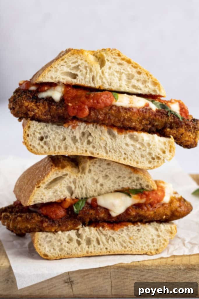 Two chicken parm sandwiches stacked on top of each other, displaying the rich fillings and golden bread.