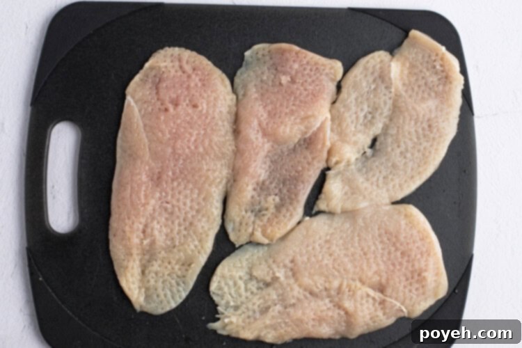 Chicken cutlets on cutting board, ready for breading.