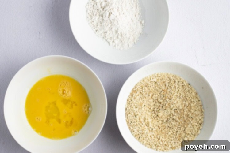 Three shallow bowls containing flour, egg wash, and breadcrumb mixture for chicken parm.