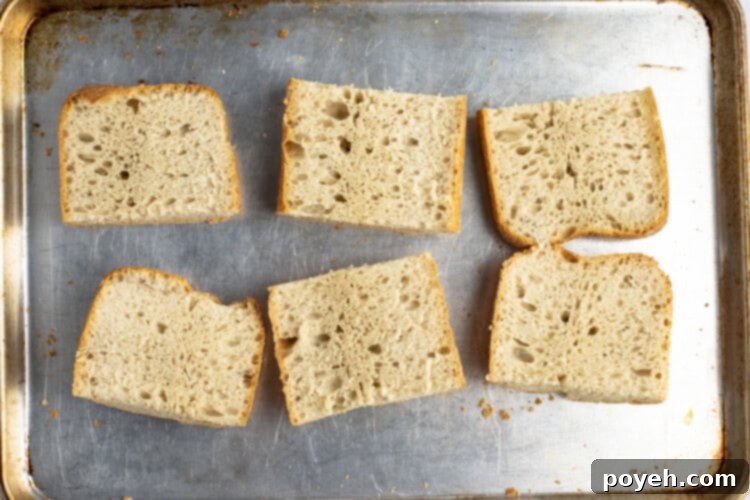 Toasted ciabatta rolls on a baking sheet, ready for assembly.