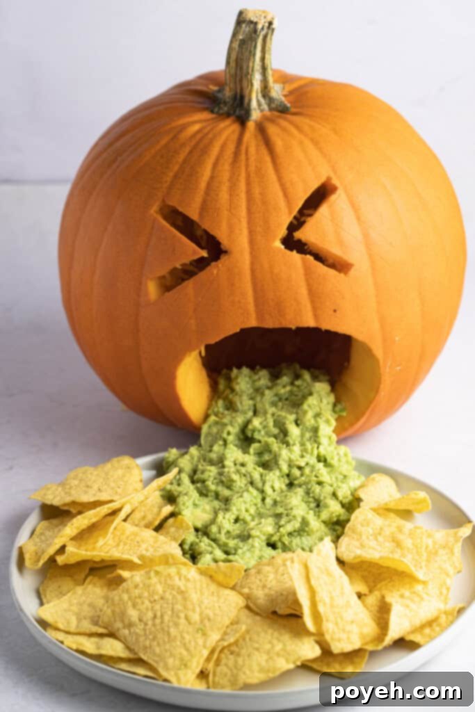 Close-up of a puking pumpkin with guacamole and tortilla chips spilling out