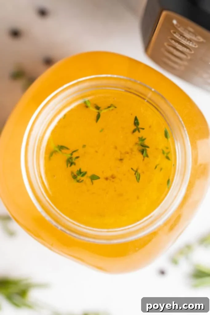 Overhead view of Instant Pot turkey stock with fresh herbs on the side, highlighting its natural goodness
