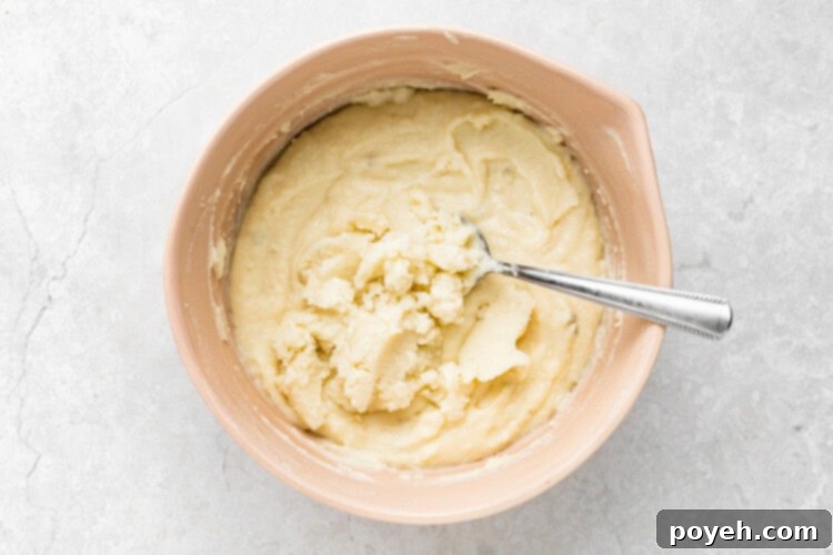 mashed potatoes in a bowl with additional freshly mashed potatoes being mixed in