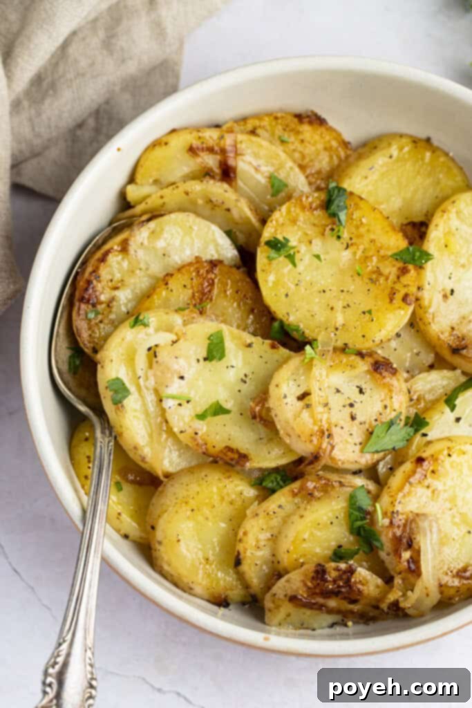 A close-up image of golden-brown smothered potatoes served in a rustic bowl, steam gently rising.
