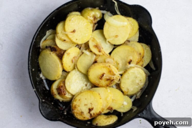 Smothered potatoes and onions sizzling in a large cast iron skillet.