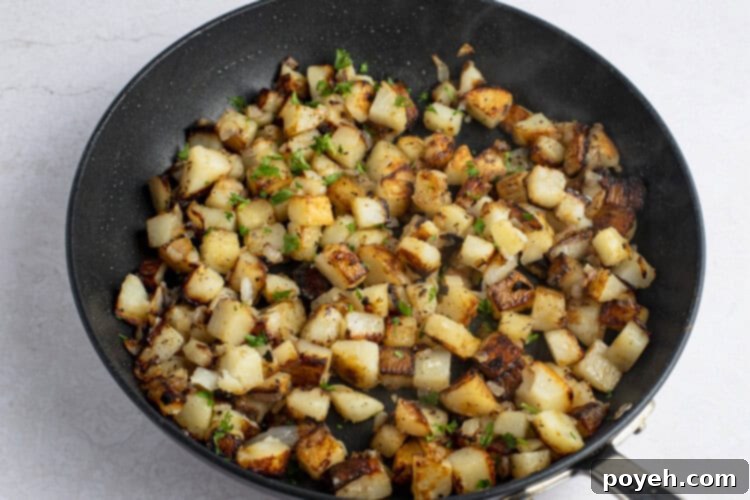 Pan-fried potatoes and onions in large cast iron skillet, cooked and ready to serve