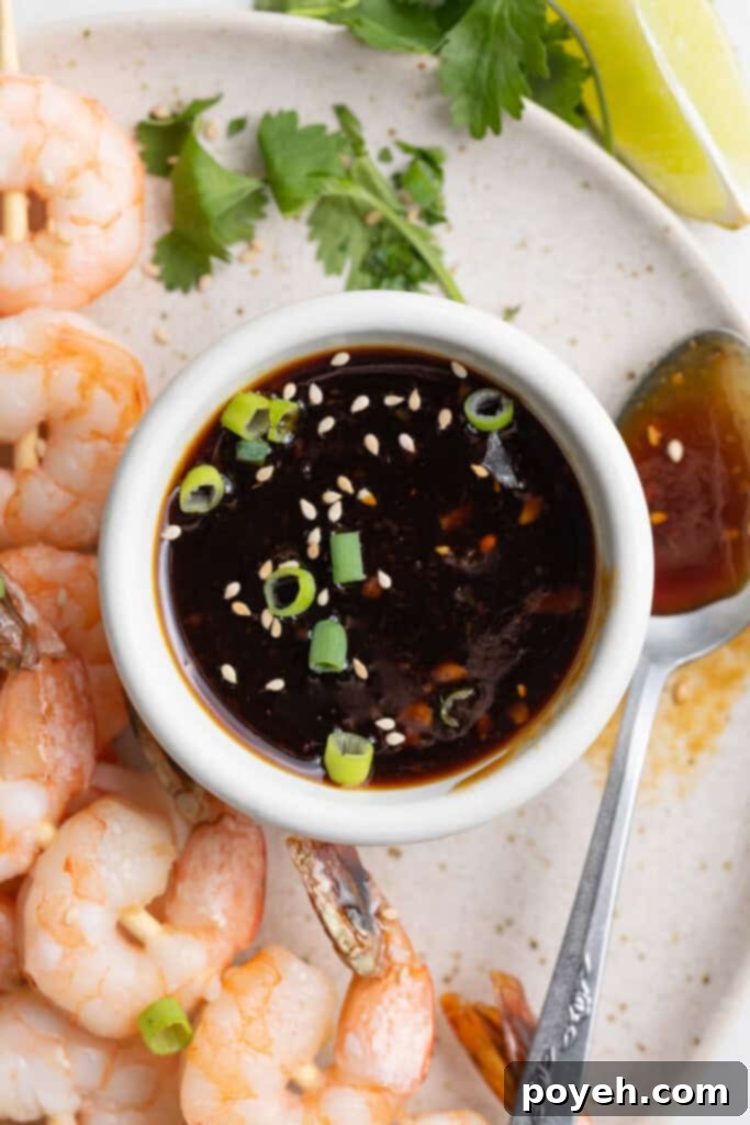 Keto teriyaki sauce served in a small white dish, with succulent cooked shrimp arranged appetizingly on the side, ready for dipping and highlighting a delicious meal pairing.
