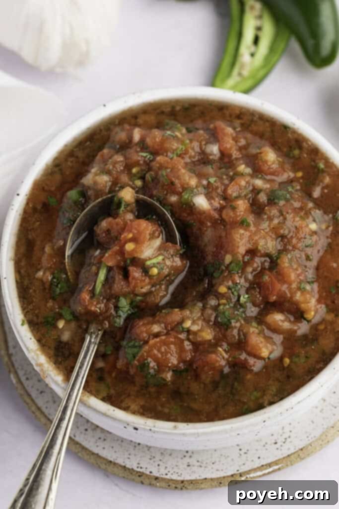 Overhead view of chunky keto salsa in a white bowl, garnished with a lime wedge and cilantro
