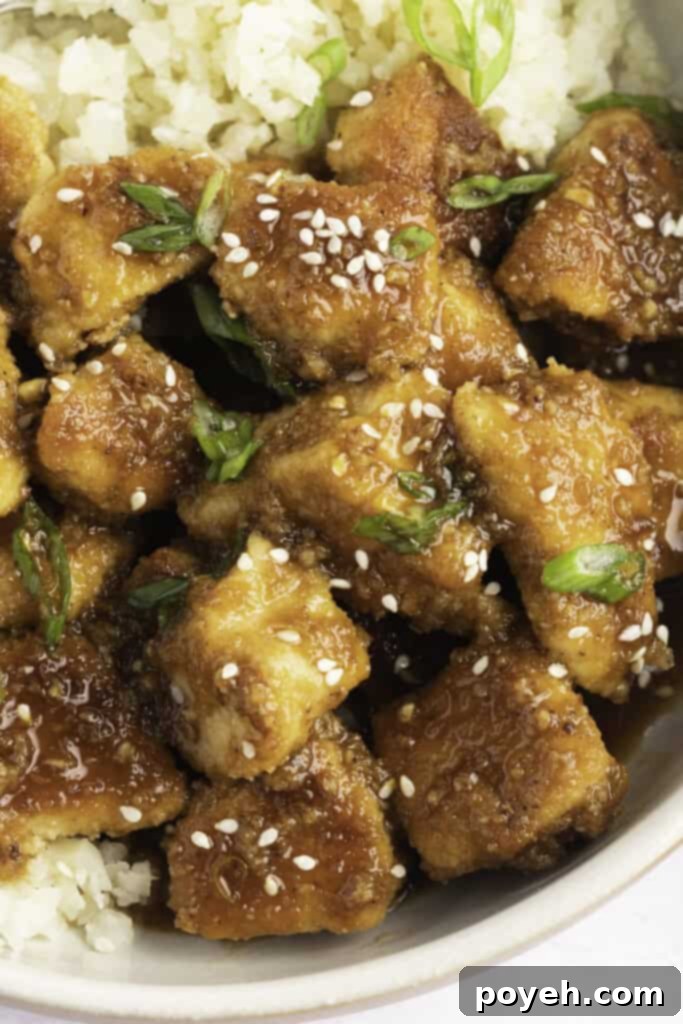 Keto orange chicken with green onions and sesame seeds on a bed of cauliflower rice