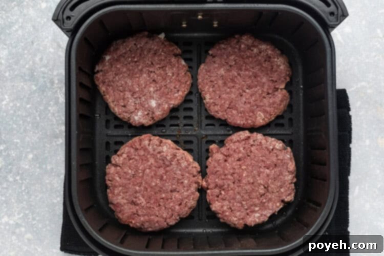 Frozen burger patties placed neatly in an air fryer basket before cooking.