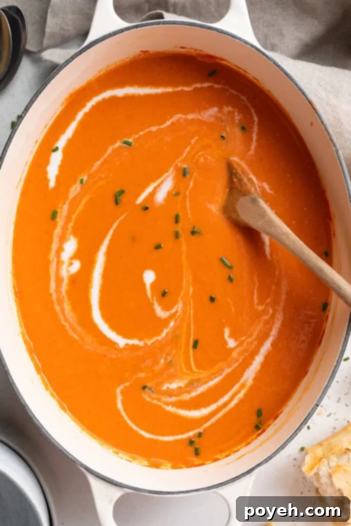 gluten free tomato soup in a large pot with heavy cream swirled on top