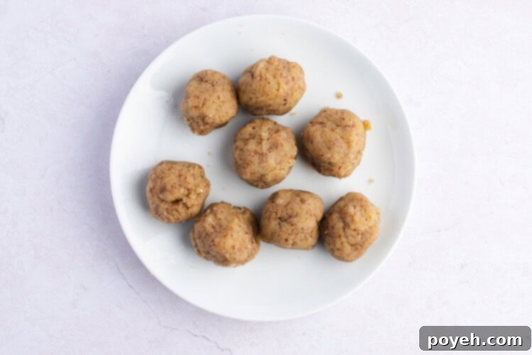 Keto masa dough rolled into individual balls, resting on a white plate, ready for assembly.