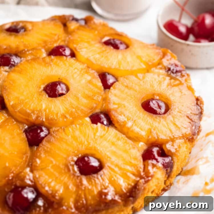 Close-up, 3/4 angle shot of a vegan pineapple upside down cake on a white table.