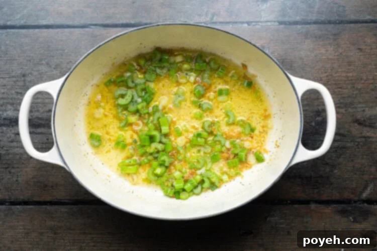 Overhead view of a large soup pot containing green onion and melted butter, gently sautéing to create the soup's flavorful base.