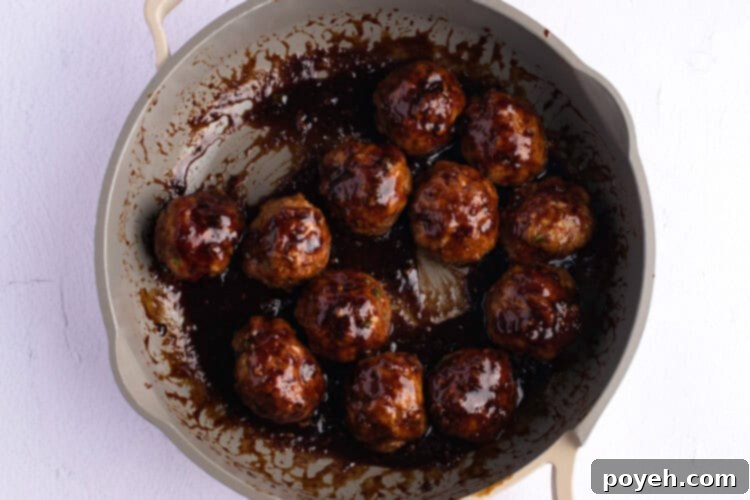 Overhead view of Asian turkey meatballs in sauce in a large skillet.