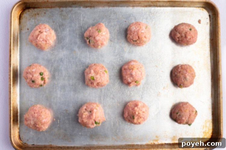 Overhead view of Asian turkey meatballs on a lightly greased baking sheet.