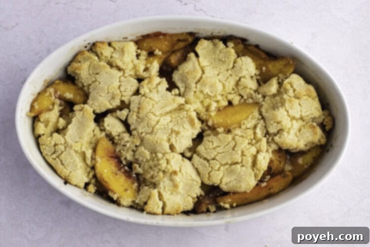 Baked keto peach cobbler in large white oval baking dish.