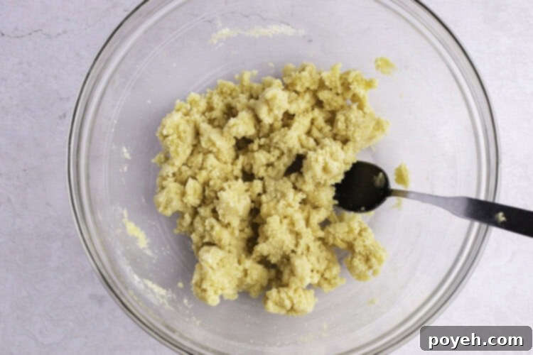 Keto cobbler crust dough in large glass mixing bowl with fork.