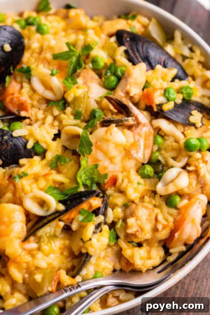 Close-up view of Instant Pot Paella on a large neutral round plate with a fork.