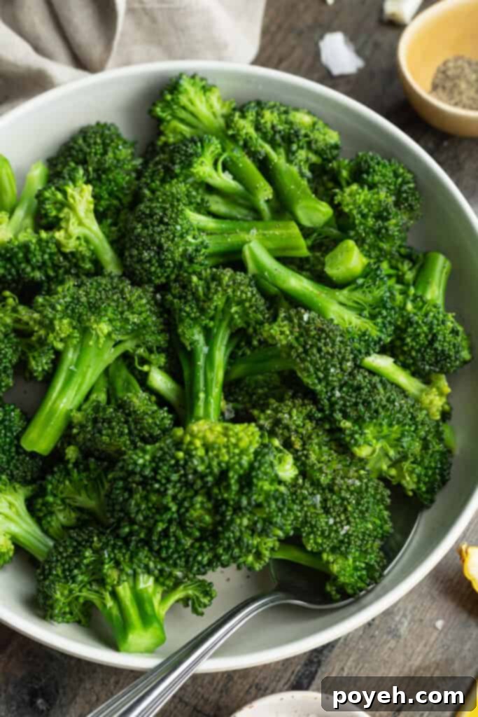 Overhead view of a bowl of sous vide broccoli on a dark tabletop, showing perfectly green florets.