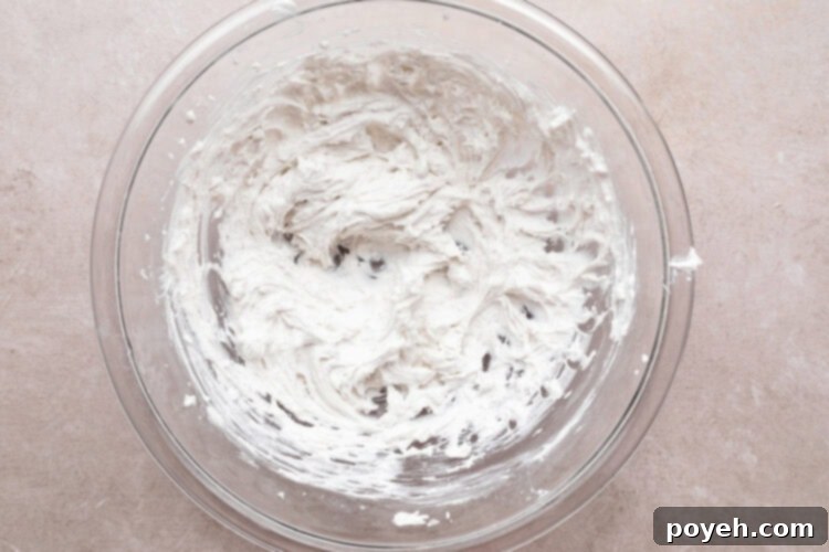 Whipped coconut cream in large glass mixing bowl.