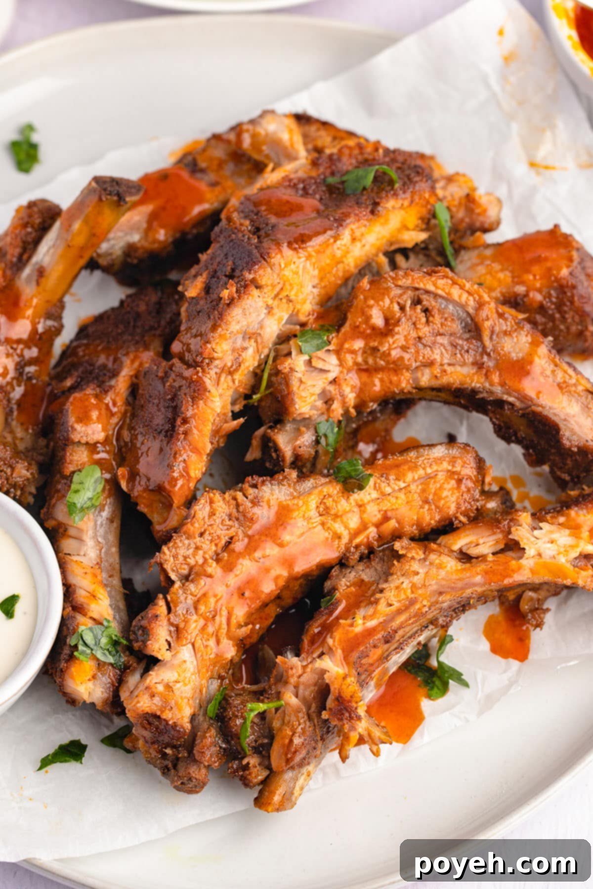 A beautifully plated serving of baked buffalo ribs, glistening with sauce, on a white plate ready to be enjoyed.