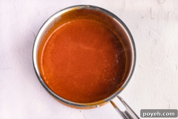 Rich, red buffalo sauce simmering in a silver saucepan.