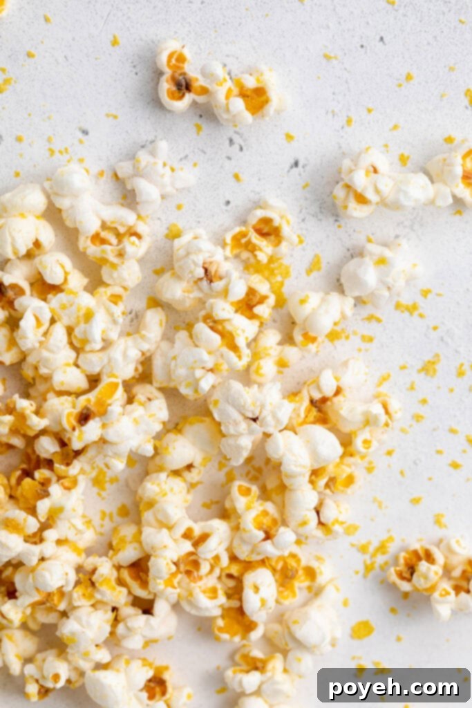 Freshly popped vegan popcorn scattered across a clean white surface, showcasing its light and airy texture.
