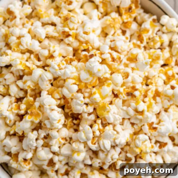 Overhead, close-up view of a large bowl of vegan buttery popcorn, generously coated with cheesy seasoning.