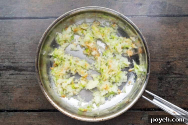 Large skillet with empanada filling ingredients on a wooden background.