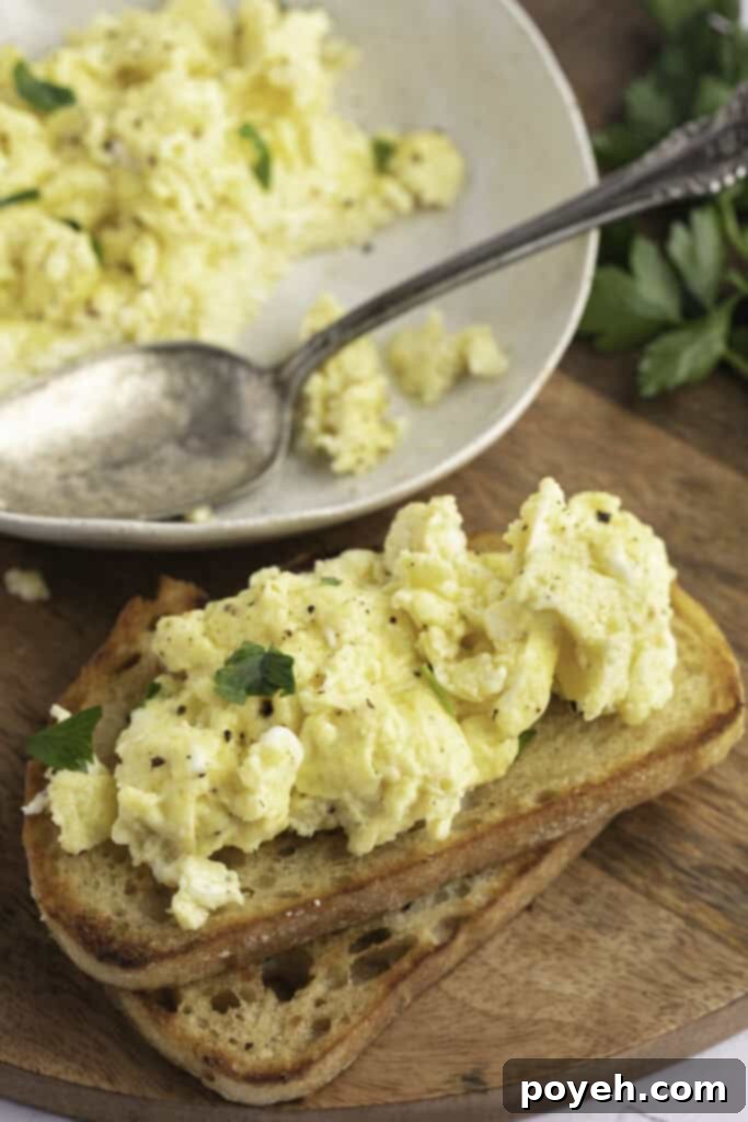 Angled view of Instant Pot scrambled eggs on toast, resting on a wooden cutting board.