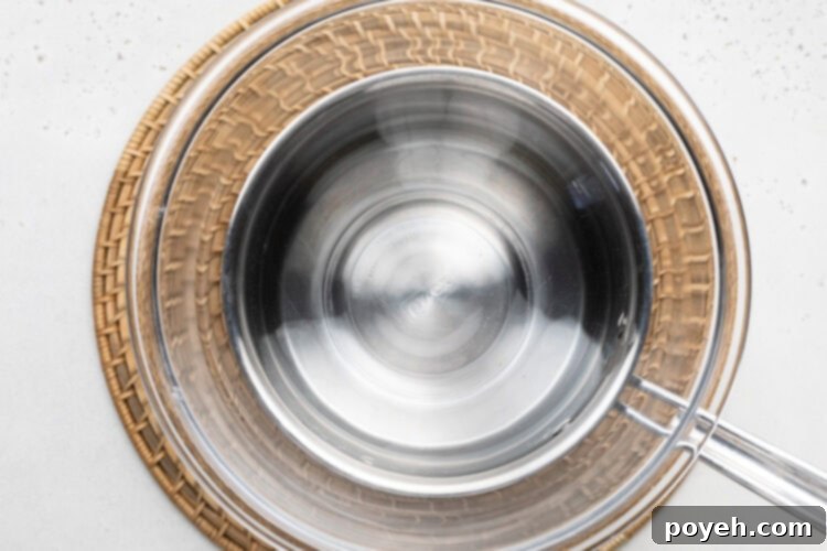 Medium saucepan with large glass bowl sitting on top.