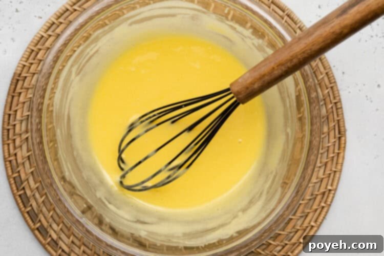 Overhead view of ingredients for keto lemon curd in a large glass bowl with a whisk.