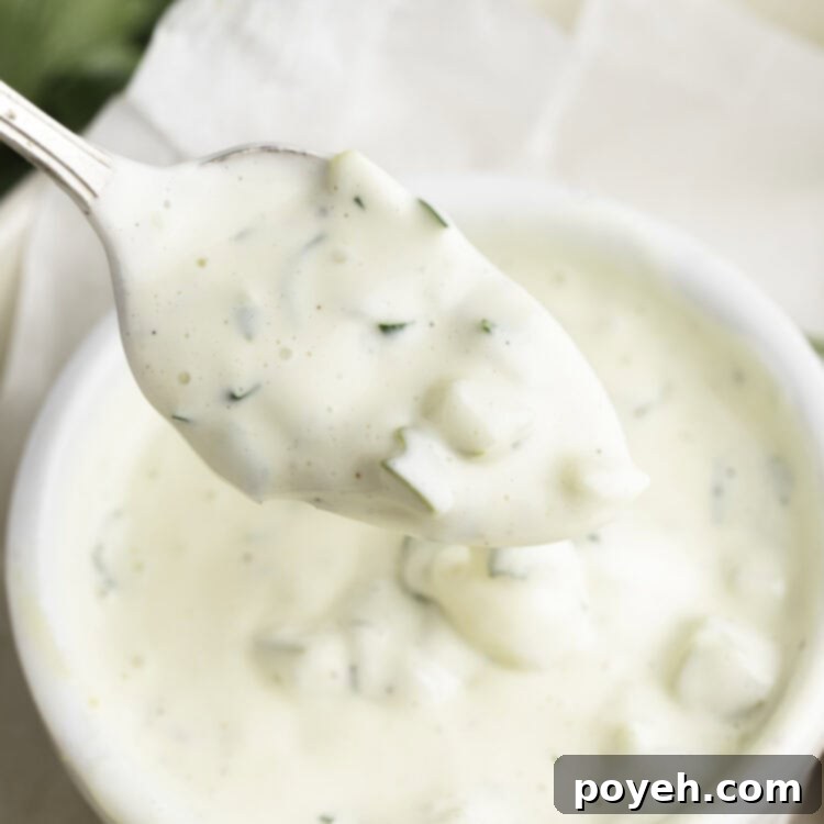 Vegan tartar sauce being lifted out of a small white ramekin on a silver spoon.
