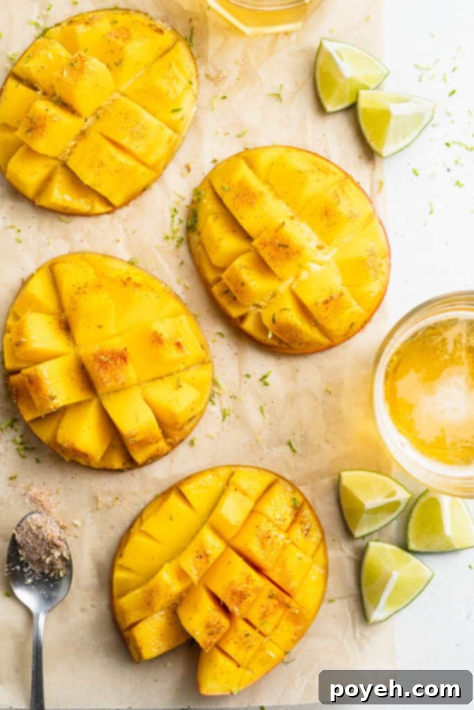 Overhead view of sliced, grilled mango on a sheet of parchment paper on a white counter, glistening with lime juice and chili-lime salt, ready to be enjoyed.