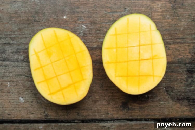Overhead view of halved and scored mangoes on a baking sheet, precisely prepared and ready for grilling.