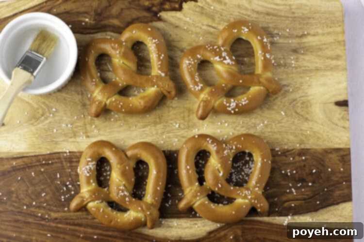 Overhead view of 4 soft twisted frozen pretzels on parchment paper, ready for the air fryer.