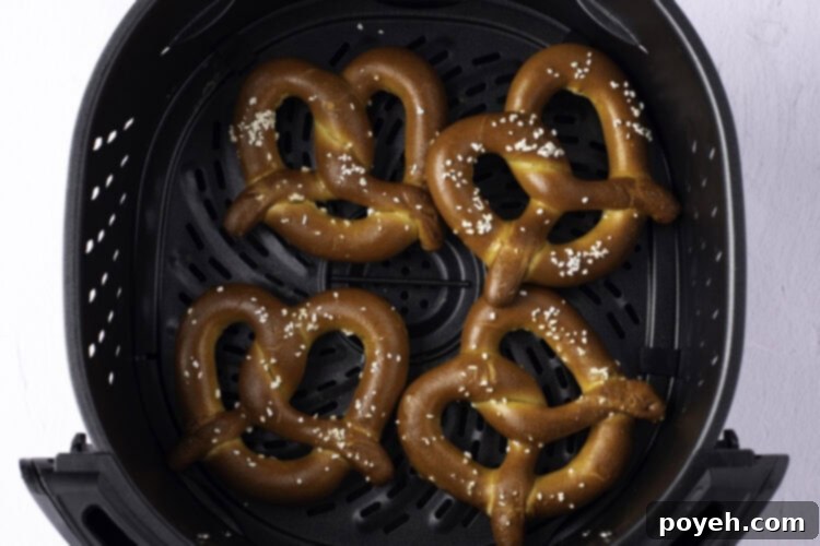 Overhead view of 4 twisted, salted, frozen soft pretzels neatly arranged in the air fryer basket.