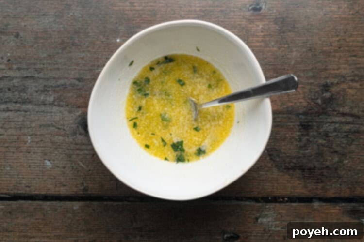 Overhead view of garlic-butter sauce in a small white bowl with a fork.