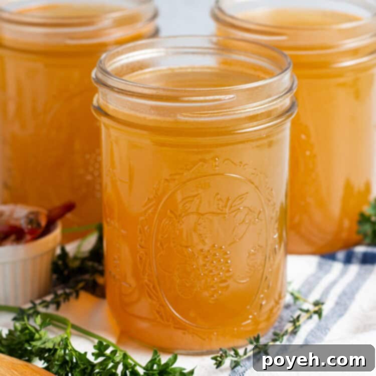 Savory Shrimp Stock from Scratch 4 Side, angled view of 3 mason jars of shrimp stock on a title surrounded by fresh herbs and a dish towel.